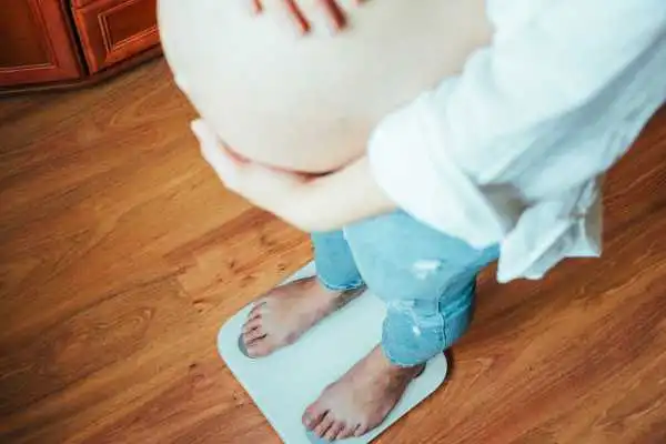 Image of woman weighing herself and experiencing weight gain through pregnancy Bedworth